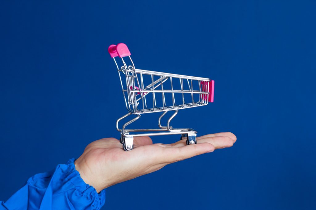 shopping cart in male hands against blue background